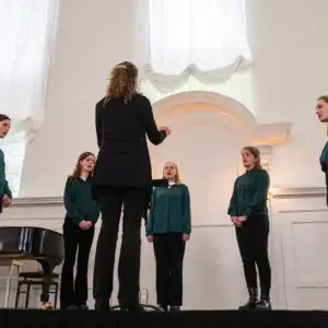 Een vrouwenkoor met dirigente.